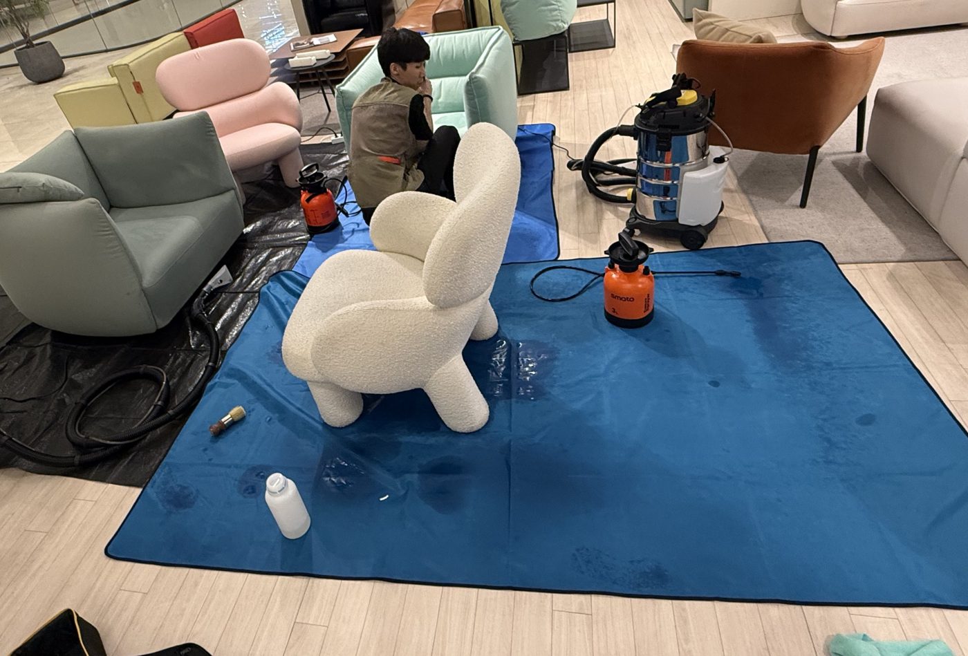 쇼룸에서 장비를 펼쳐 의자를 세척하는 청소공방 기술자